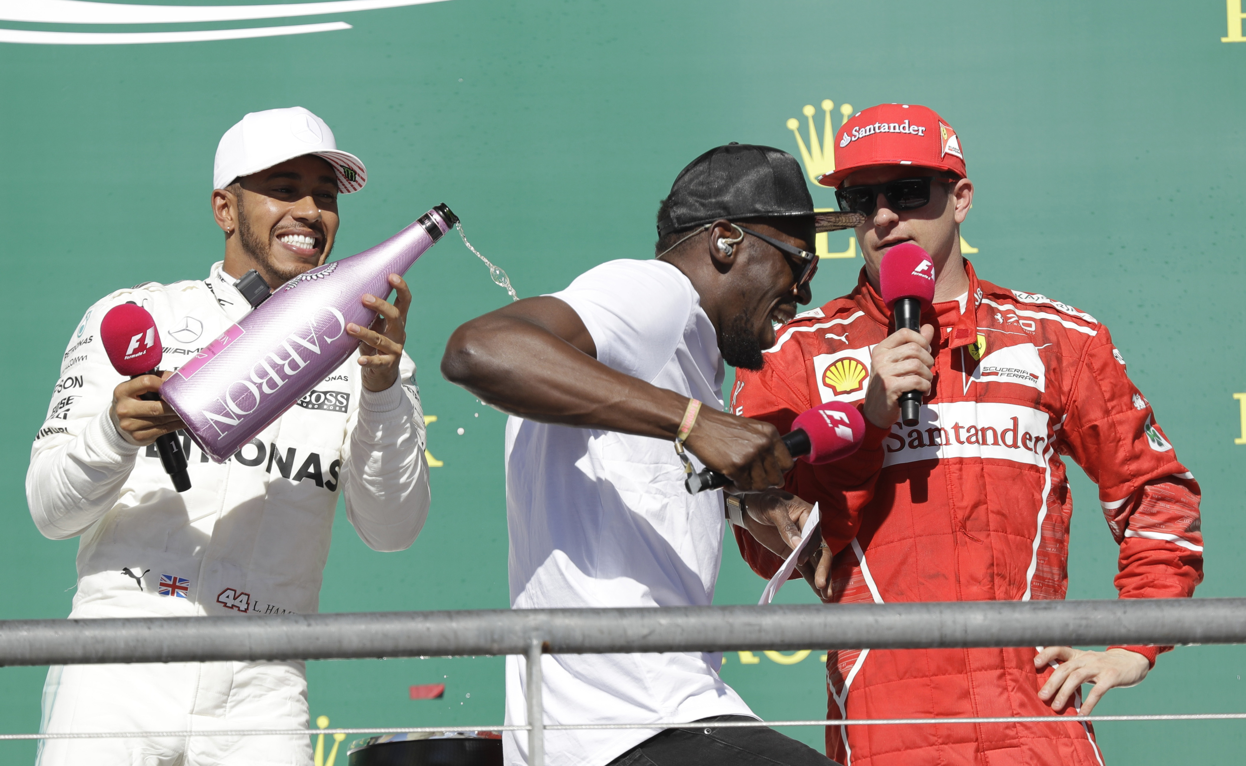 Mercedes driver Lewis Hamilton, left, of Britain, douses Usain Bolt, center, as he celebrates his win in the Formula One U.S. Grand Prix auto race at the Circuit of the Americas- AP